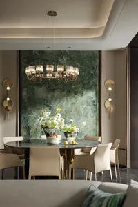 A modern luxury dining room featuring a round table, white chairs, and a chandelier hanging from the ceiling.