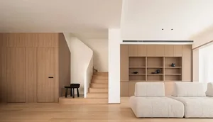 Modern minimalist living room with white furniture and wooden elements.