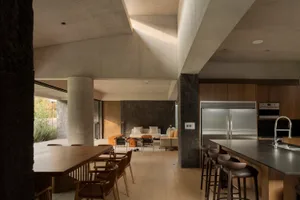 Contemporary residential interior featuring concrete walls and wooden dining area.