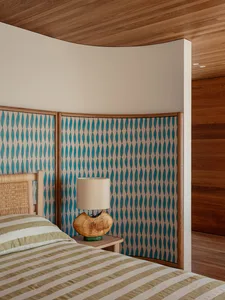 An industrial-style bedroom with a patterned wooden headboard and striped bedding.