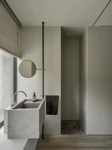 Modern minimalist bathroom featuring a concrete sink and metal fixtures.