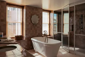 Minimalist bathroom featuring a white bathtub with a chrome tap and a shower enclosure within a tiled space.