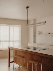 A minimalist residential kitchen with a wooden island and marble countertop.
