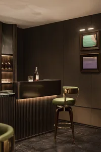 Modern bar with a marble counter, green stools, and framed abstract art in dark interior design space.