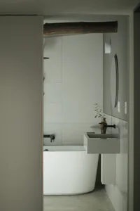 Minimalist bathroom with concrete walls and a freestanding white bathtub.