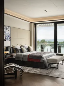 A modern bedroom with fabric bedding, a wooden floor, and a glass door overlooking a scenic landscape.