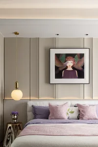 Modern bedroom featuring a bed with blush velvet bedding, white and pink pillows, and a modern chandelier and artwork on the 