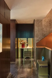 Modern minimalist entryway featuring a marble floor, a green console table with a red vase containing dried flowers, and a bl
