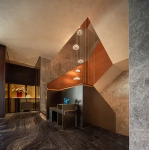 Indoor hotel lobby with marble floors and concrete walls, modern lighting fixtures, and a decorative blue lion statue.
