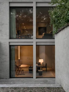 A modern interior space featuring concrete walls, glass windows, and wooden furniture.