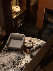 A modern living room with two upholstered armchairs, a coffee table, and a rug with a gray fabric pattern.