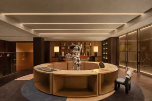 A modern lobby featuring a wooden circular counter with a metallic statue on it.