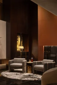 A modern lounge area with two fabric-covered lounge chairs on a textured fabric rug, featuring a marble coffee table and a co