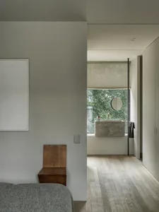A modern minimalist bathroom featuring a stone sink and mirror.