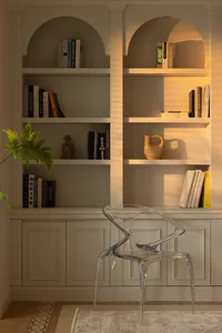 A minimalist library with a glass chair, white shelves, wooden vase, and white painted walls and panels.