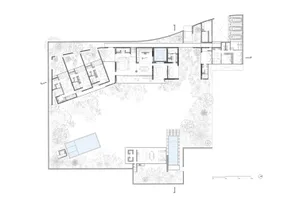 Floor plan of a modern residential building with various rooms and outdoor spaces.