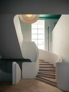 A modern staircase with white concrete walls, wooden steps, and a wicker lampshade hanging overhead.