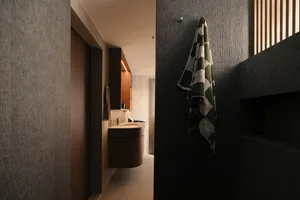 A modern minimalist bathroom with concrete walls, a sink vanity, and a patterned towel hanging on the wall.
