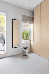A minimalist bedroom featuring sleek concrete and wooden furniture, with a soft, textured rug.