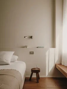 Minimalist bedroom with white canvas walls, wooden furniture, and glass elements.