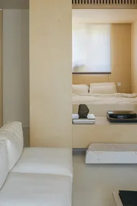 A minimalist bedroom featuring a wooden platform bed and white furniture.