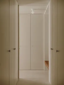 A minimalist hallway with concrete flooring and walls, featuring a central light fixture.