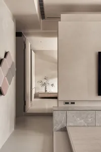 A minimalist living room with concrete walls and floor, featuring a wall-mounted TV and a floating shelf.
