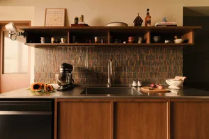 A modern kitchen with a wooden backsplash featuring various kitchen utensils and ingredients, including sunflowers, onions, a