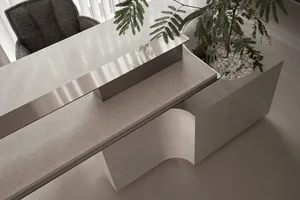 A modern office desk made of concrete with a plant and pebbles in a base.