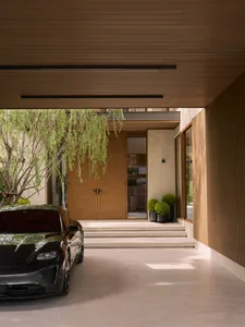 Modern residential entry featuring wooden walls and a black electric car parked outside