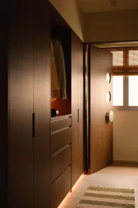 A minimalist closet space featuring wooden cabinets and drawers with a light interior illumination.