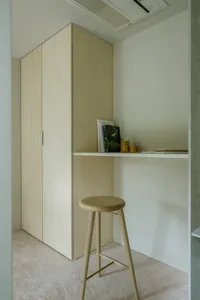 A minimalist home office setup with a wooden desk and stool.