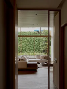 Modern cozy living room with a textured sofa and large windows overlooking a green outdoor area.