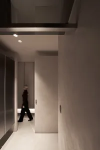 A minimalist hallway with a concrete floor, viewed from the side, featuring subtle lighting.
