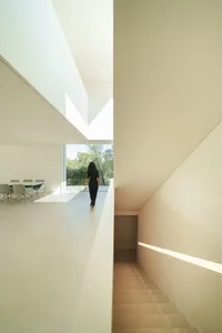 A modern interior design featuring a white concrete staircase and minimalist decor.