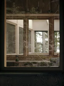 A modern interior space with a large window made of wood, looking out into a forested area.