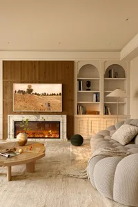 A modern living room with a neutral color palette, featuring a cozy sofa, a round wooden coffee table, and a built-in bookshe