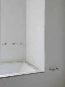 A minimalist bathroom with white tiles and gray concrete accents.