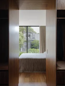 A minimalist bedroom featuring a stripped bed and wooden paneling.