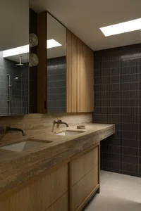 Modern residential bathroom featuring a stone countertop sink with wall-mounted faucets and vertical wood wall paneling.