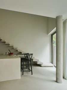 A modern indoor space with concrete elements and black bar stools.
