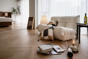 Modern interior design featuring a cozy white sofa, books, and wine glass on a wooden floor.