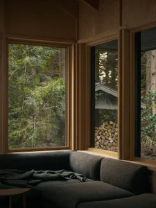 A modern interior design featuring wooden window frames and a cozy sofa with a blanket.