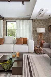 Modern living room featuring a white sectional sofa with brown cushions, a striped rug, and a stone accent wall.