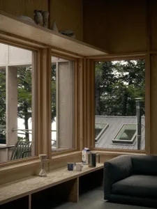 A modern living room featuring a wooden window sill with a view of trees outside and a grey armchair.