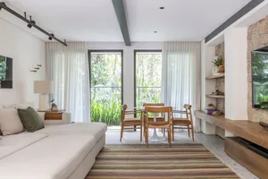 Modern living room with wooden furniture, white curtains, and a striped rug.