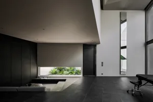 A minimalist interior design featuring a modern concrete floor and walls, with a small window showing greenery outside.