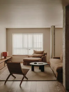 Modern living room featuring a comfortable sofa on concrete flooring with soft furnishings and minimalistic design elements.