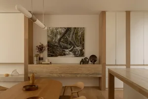 Modern living room with neutral tones, featuring a central artwork and wood accents.