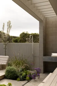 Modern outdoor shower space featuring concrete structures and lush greenery.